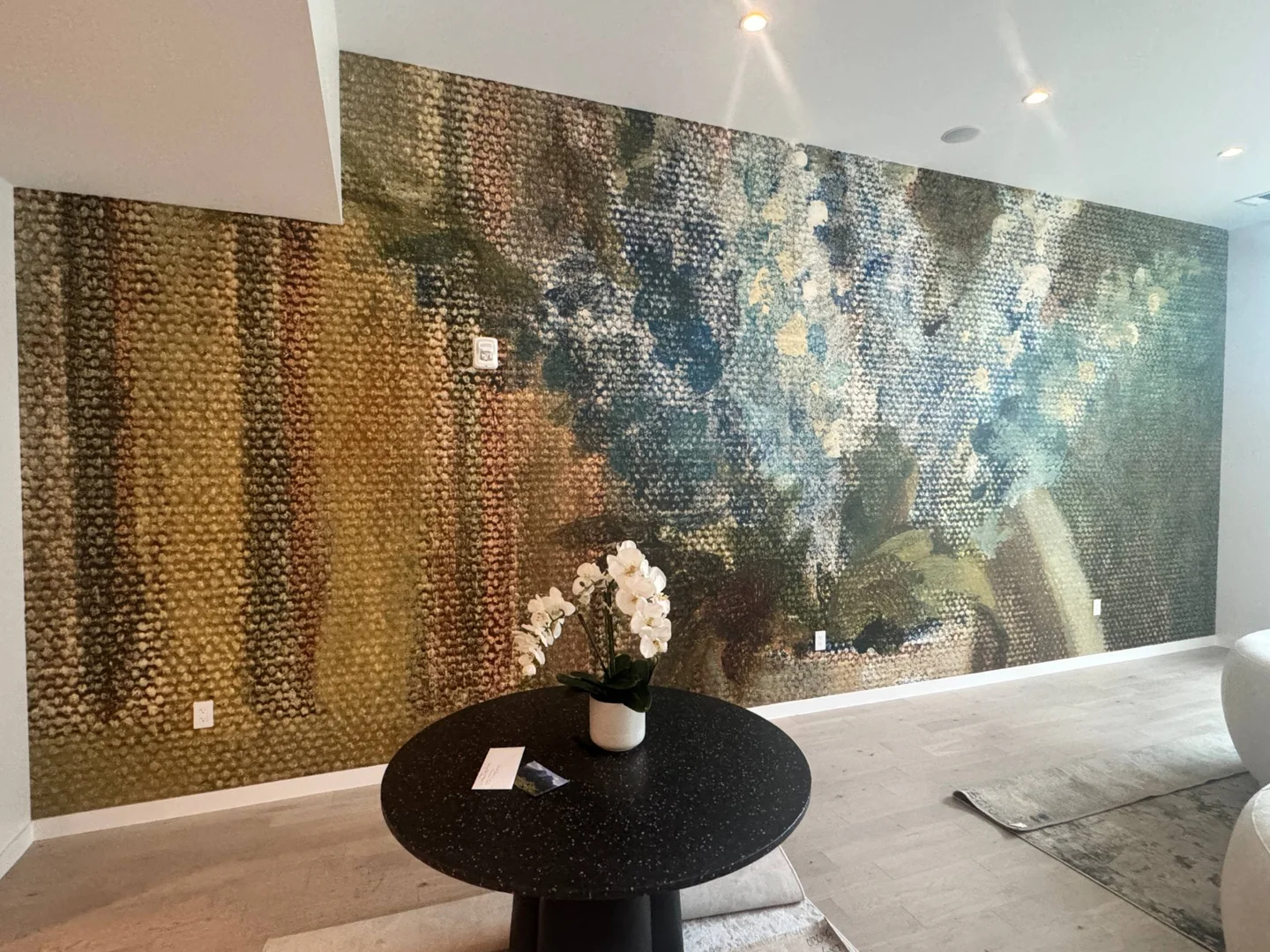 Abstract patterned wallpaper across a living room wall behind a round table and white orchid