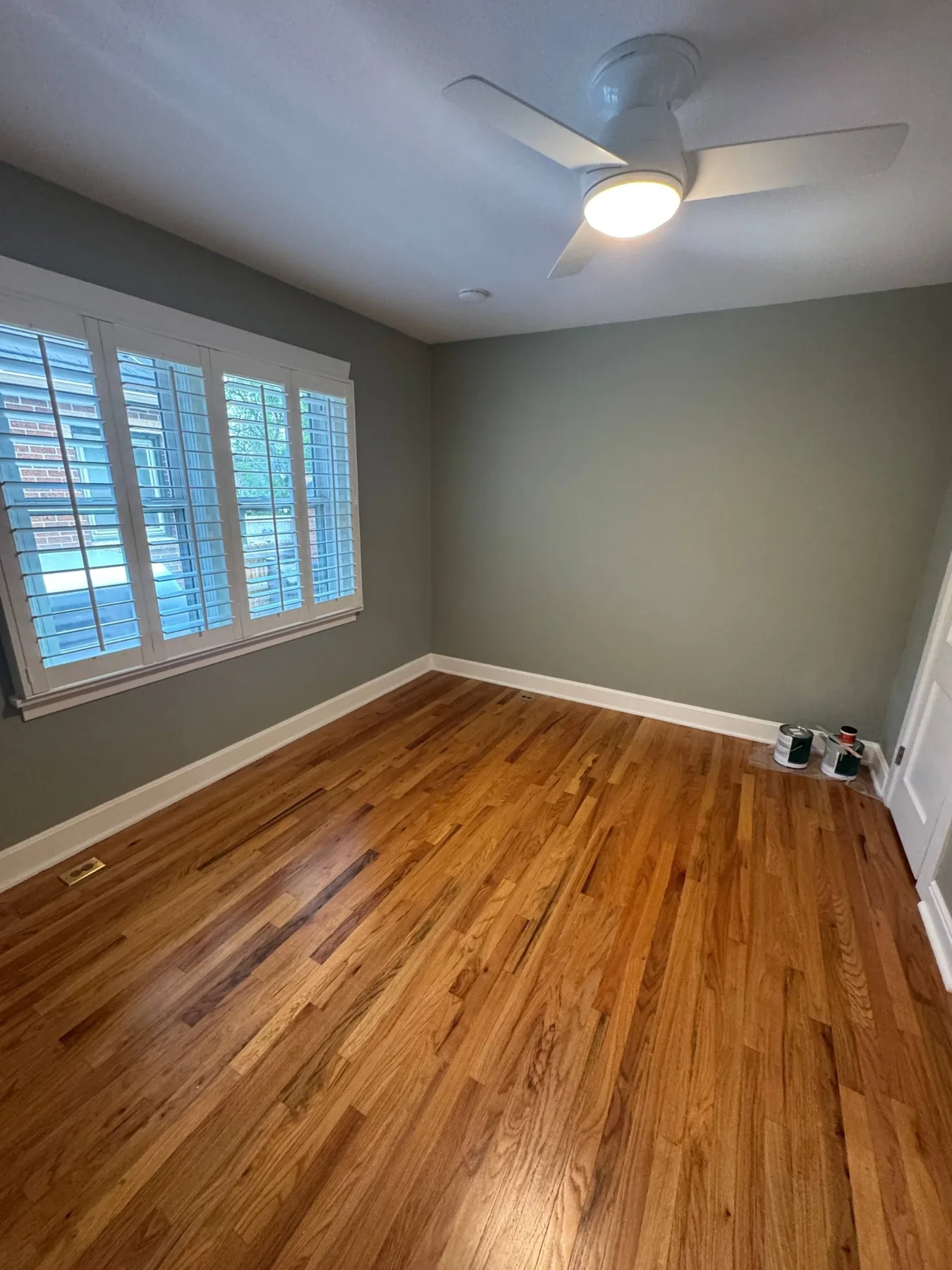 Interior room with grey-green painted walls, white trim and wood flooring