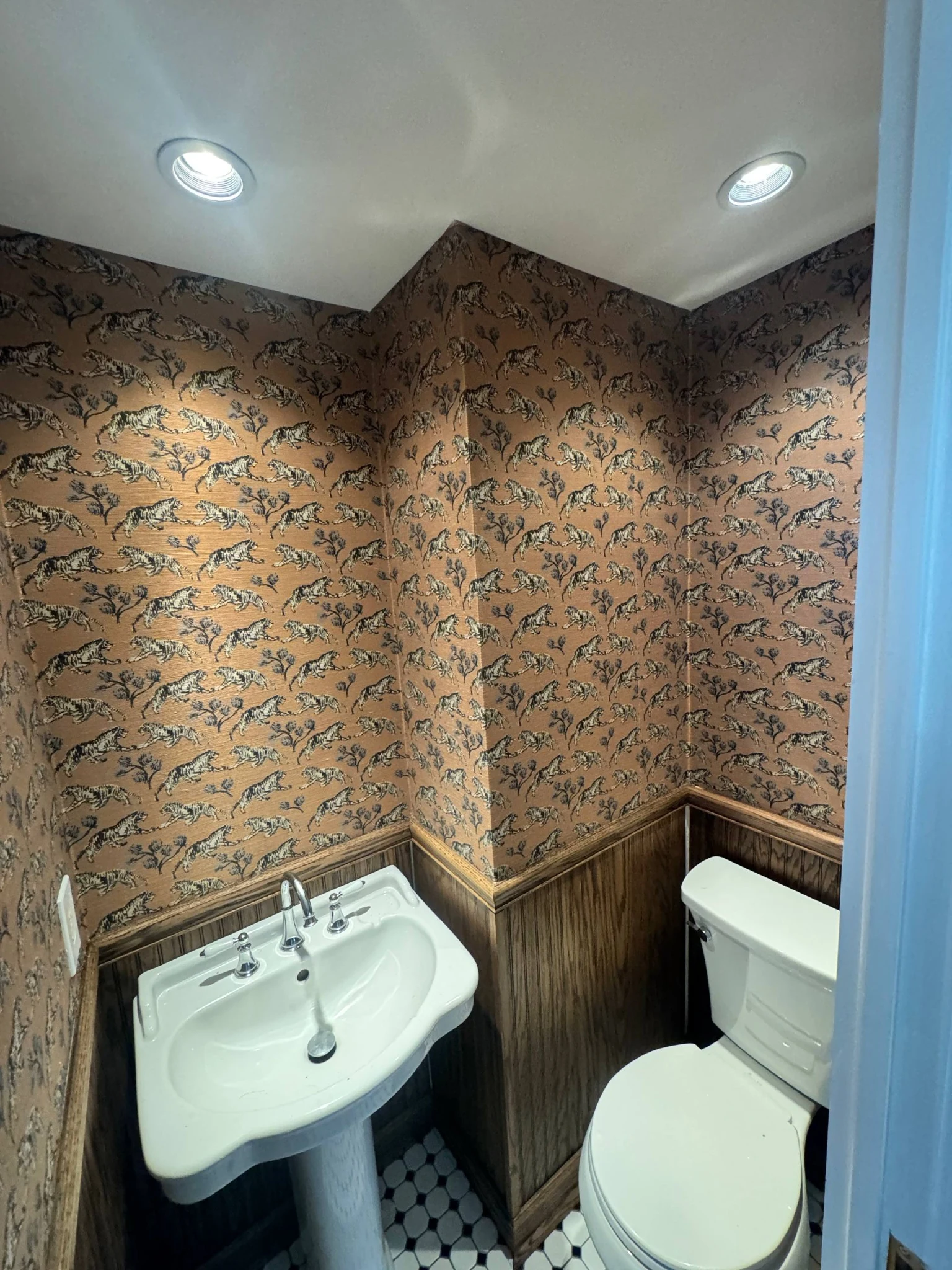 Tiger-pattern wallpaper fitted around inside and outside corners above wood panelling in a powder room