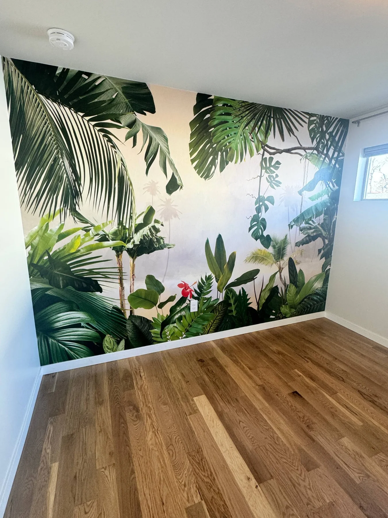 Floor-to-ceiling tropical leaf wallpaper on an accent wall